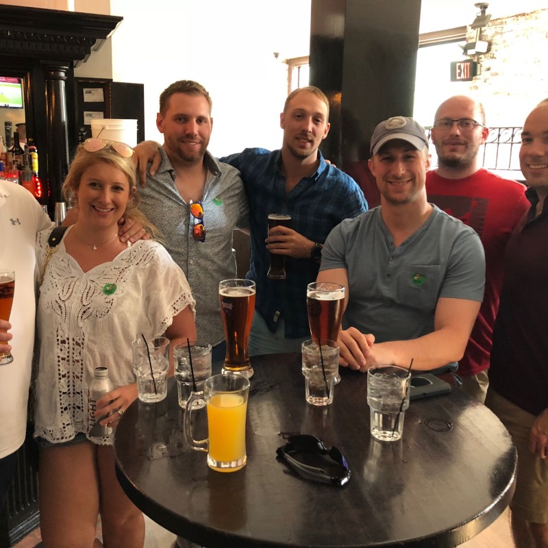 a group of people standing next to a bottle of wine